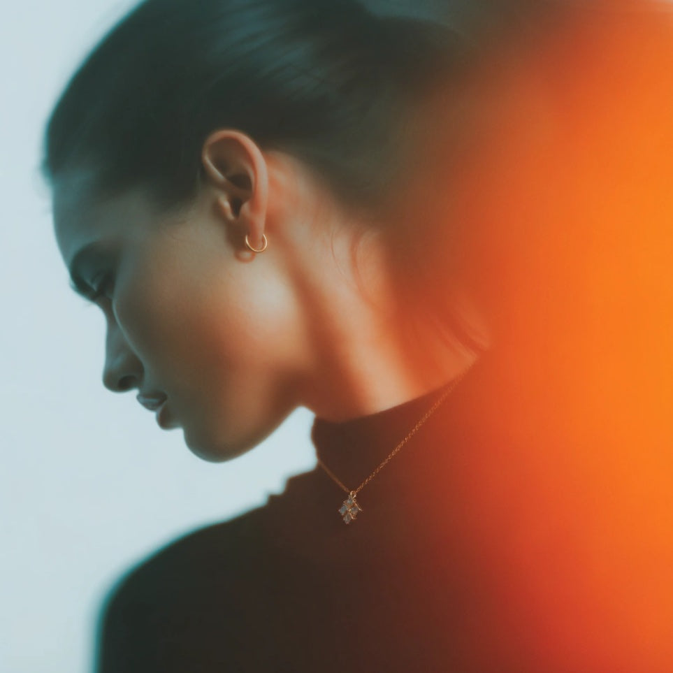 A fine gold hoop earring and a pendant necklace worn together